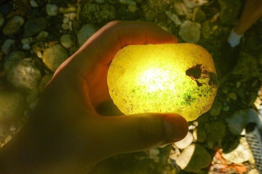 A hand holding a yellowish translucent object with a rough texture. 4