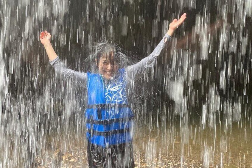 Een persoon in een blauw redvest met gespreide armen, staand in water met motregen. 4