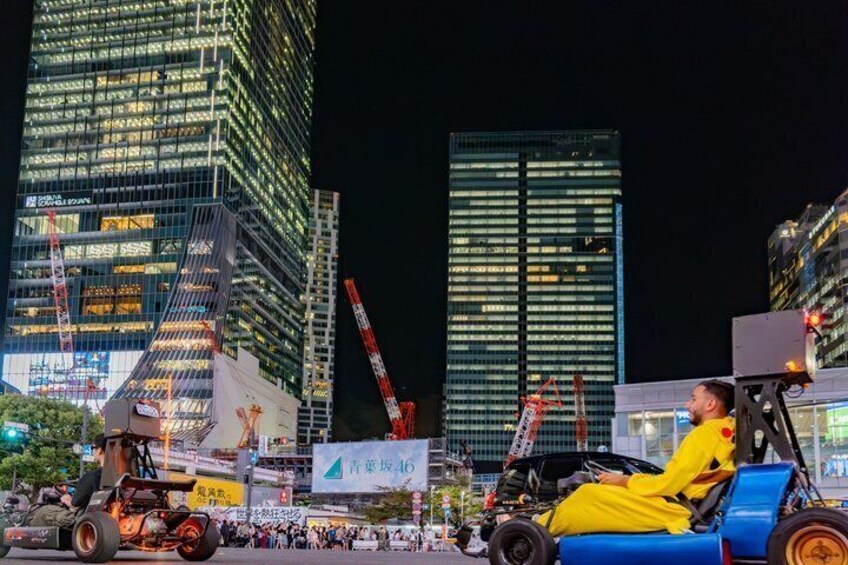 A nighttime cityscape with illuminated skyscrapers, a construction site with cranes, and a person in a yellow costume on a blue vehicle. 3
