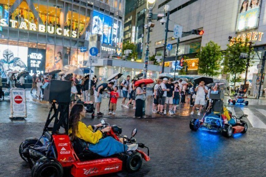 A street with people, a go-kart, and a Starbucks. 4