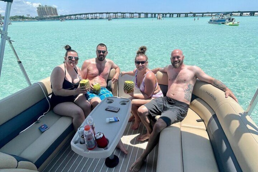Un grupo de personas en un barco, con una mesa que tiene bebidas y una piña. 5