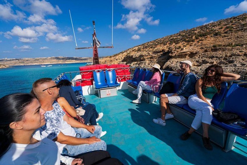 Mensen in een boot, met een rotsachtig landschap en helderblauw water op de achtergrond. 3