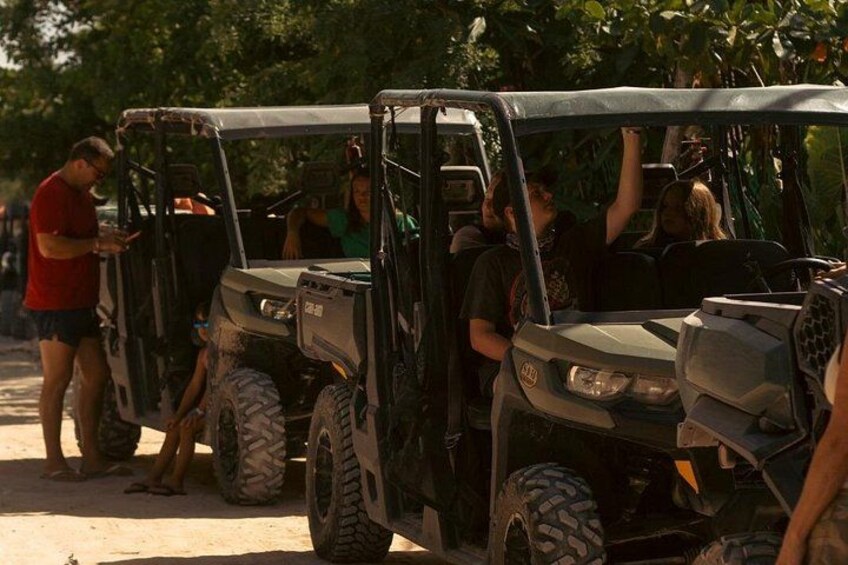 A group of off-road vehicles parked on a dirt path with people around them. 4
