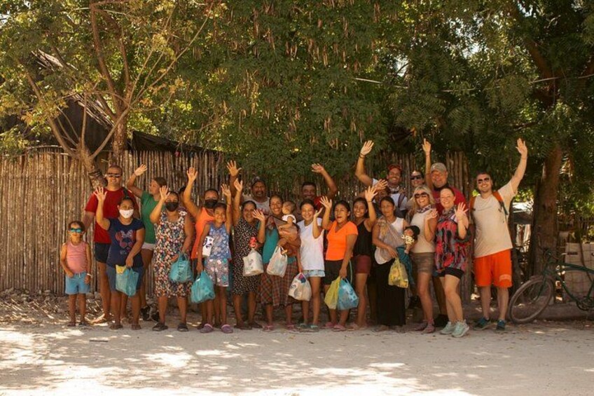 A group of people standing outdoors, some with raised hands, under a tree. 3