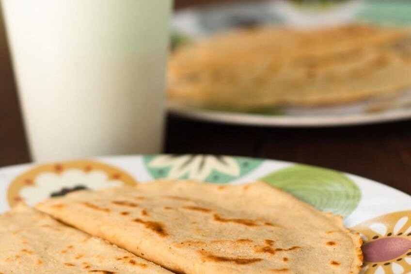 A plate with folded crepes and a cup of milk. 5