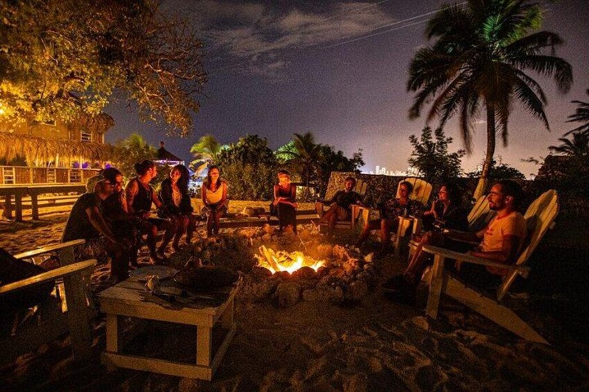 A group of people sitting around a campfire at night. 4