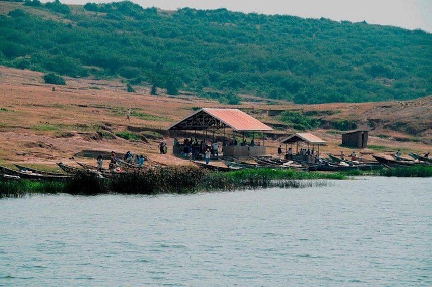 A riverside scene with boats, a covered structure, and a hilly background. 2