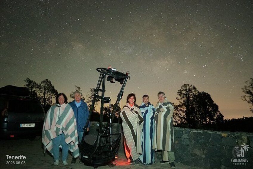 A group of people standing under a starry sky with a vehicle in the foreground. 2