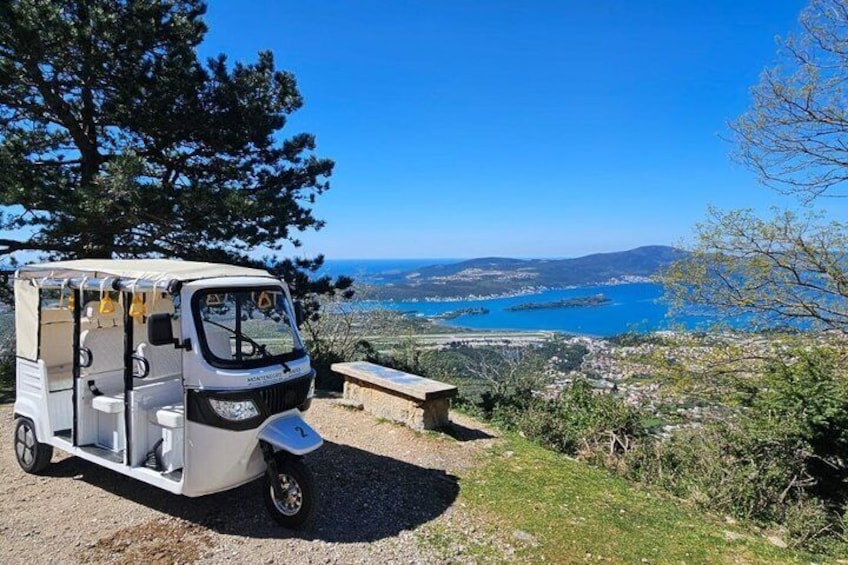 A white camper van parked on a gravel path with a scenic view of a coastal landscape and a body of water in the background. 3