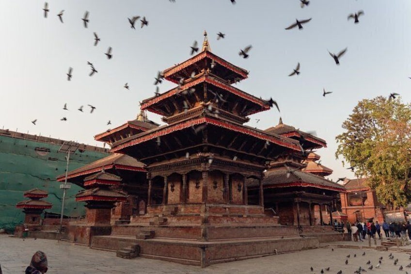 Un temple à plusieurs niveaux, de style architectural traditionnel, entouré d’une foule de personnes et de pigeons. 3