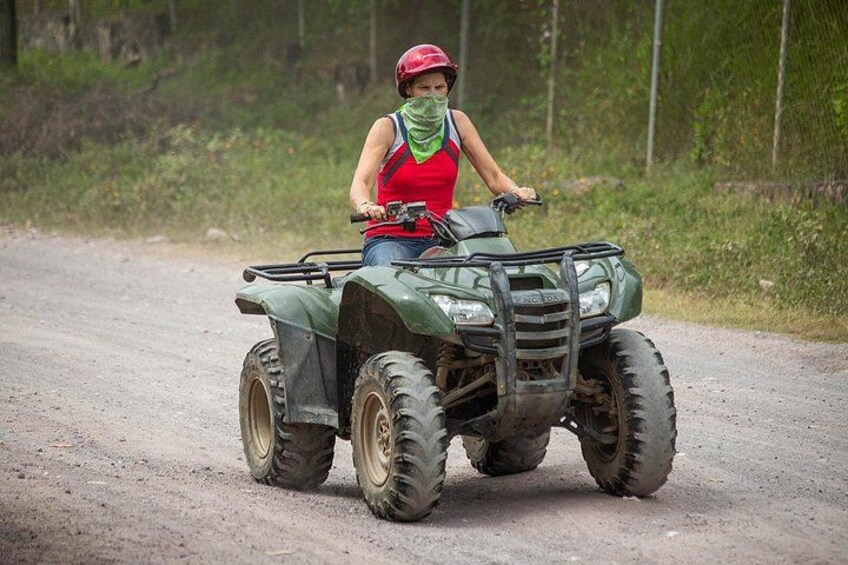 Une personne conduit un quad vert sur un chemin de terre. 2