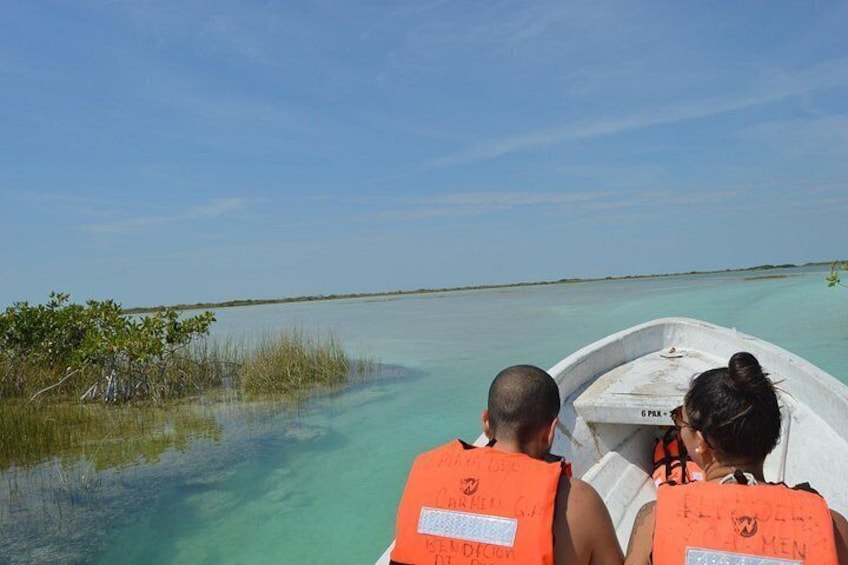 A boat with two people wearing life jackets, a calm sea, and a clear sky. 4