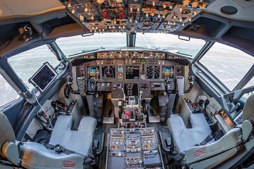 Cockpittet i et fly med flere kontrolpaneler, et stort loftpanel og to pilotstole. 4