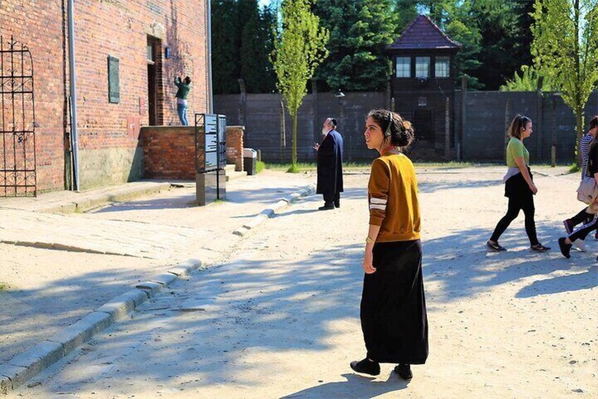 A person in a yellow sweater and black skirt walking on a dirt path. 1