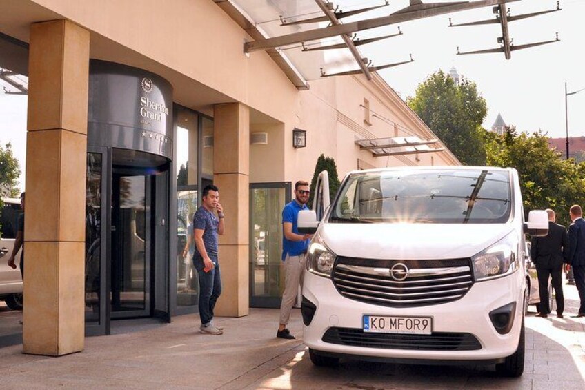 A white van parked in front of a building with a sign that reads 'Sheraton Grand.' 5