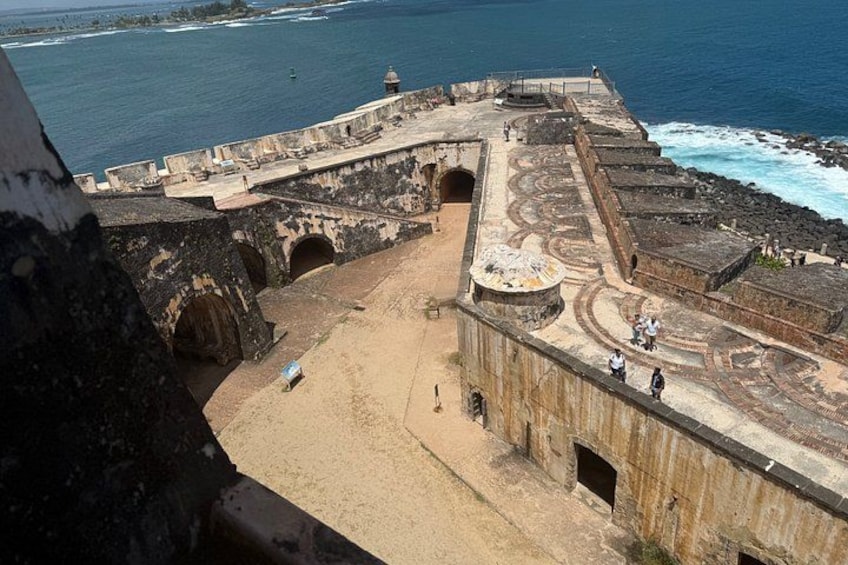 A coastal fortification with a sandy beach, a large circular structure, and a lighthouse. 4