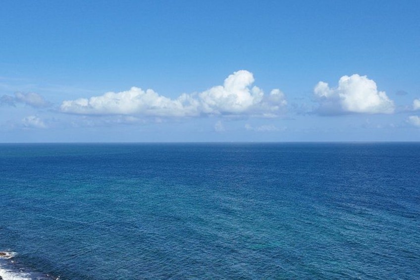 A clear blue ocean under a bright sky with scattered clouds. 5