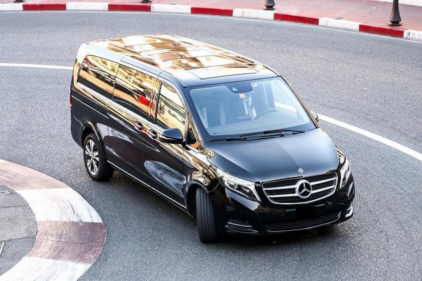 A black Mercedes-Benz van parked on a road with a red and white curb. 2