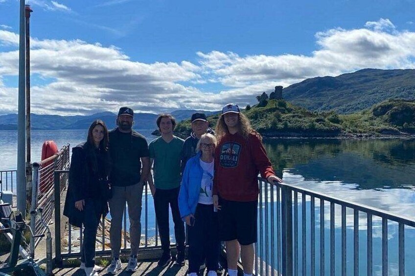 Un grupo de personas en un muelle, con un lago y colinas al fondo. 4