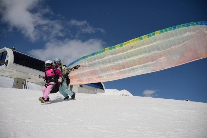 Un planeador con alas de colores sobre una ladera nevada. 3