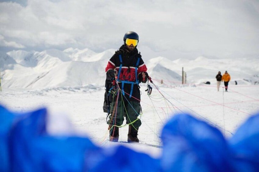 Una persona con chaqueta roja y negra y casco, sosteniendo un arnés y cuerdas, preparándose para una actividad de escalada en montaña. 4