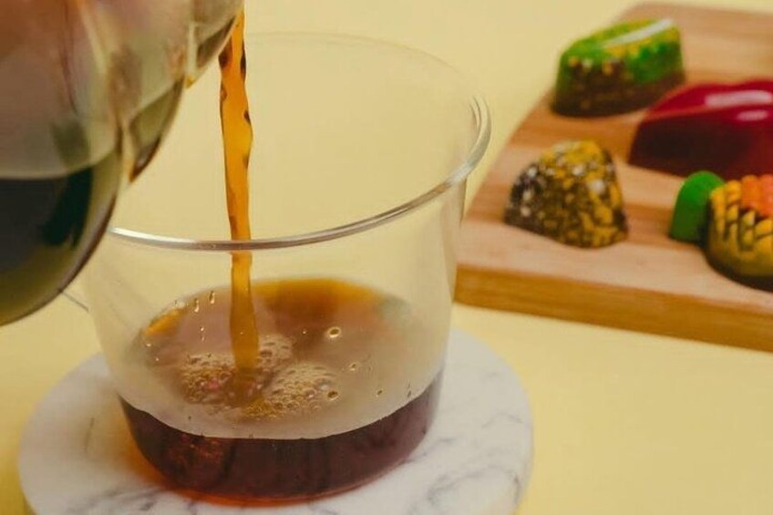 Een helder glazen glas op een marmeren onderzetter, met een donkere vloeistof die erin wordt gegoten. 3