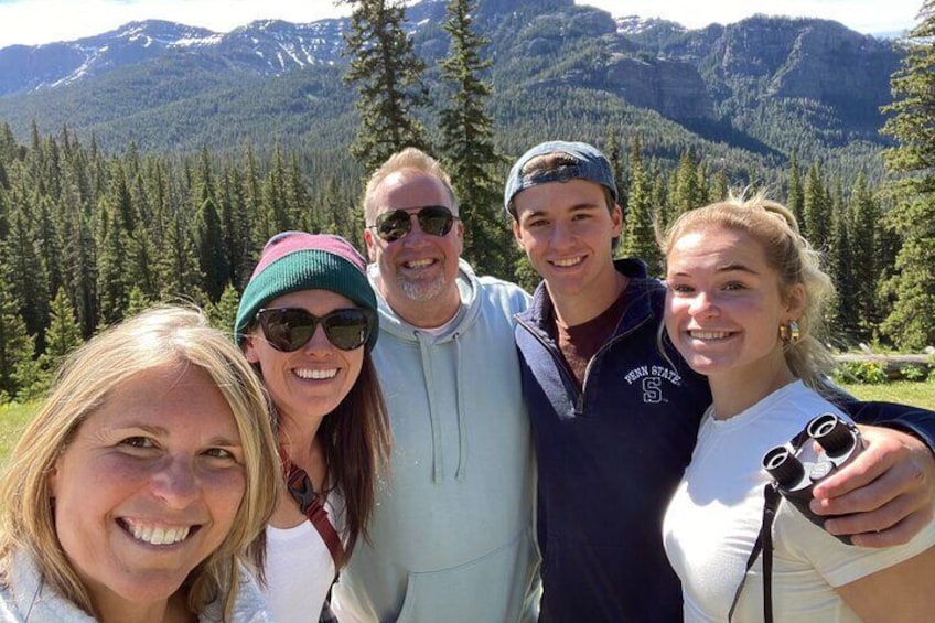A group of people standing outdoors with a mountainous landscape in the background. 1