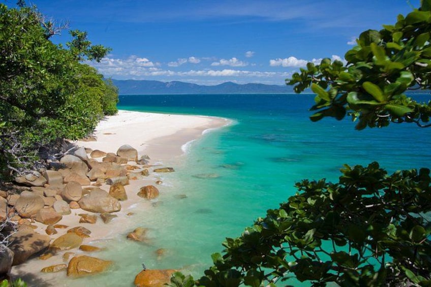 Une plage avec une eau turquoise et limpide, du sable blanc et de gros rochers. 1