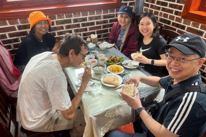 Un groupe de personnes est réuni autour d’une table, où se trouvent divers plats. 5