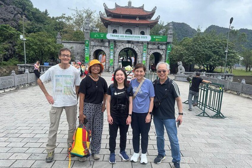 Un groupe de personnes se tient devant une porte traditionnelle, sur laquelle est apposée une pancarte indiquant le « Marathon de Trang An 2025 ». 4