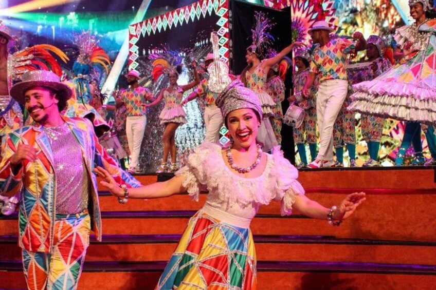 A group of people in colorful traditional costumes performing on a stage. 2