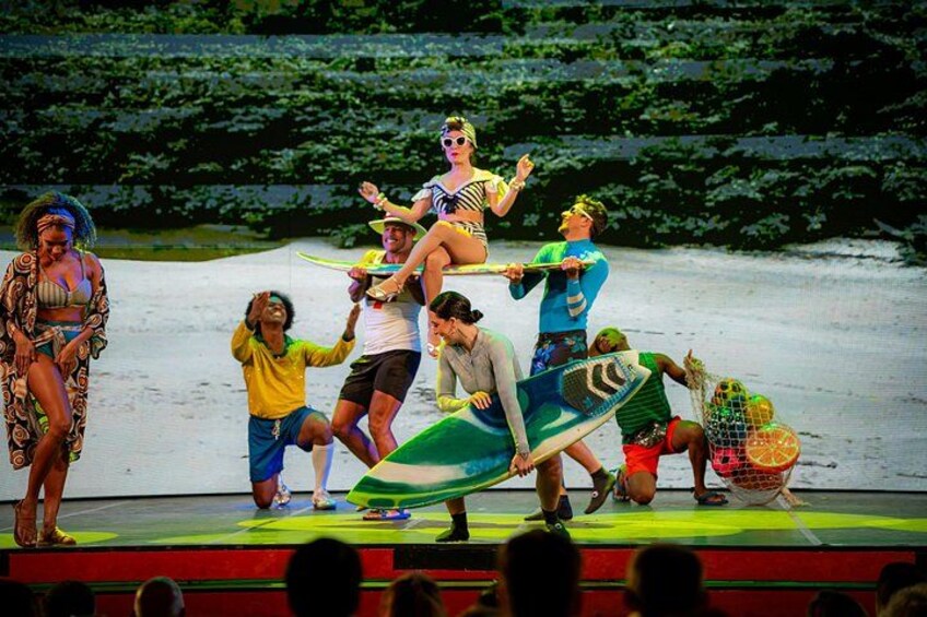 A stage performance with people in costumes and props, including a surfboard and a net. 2