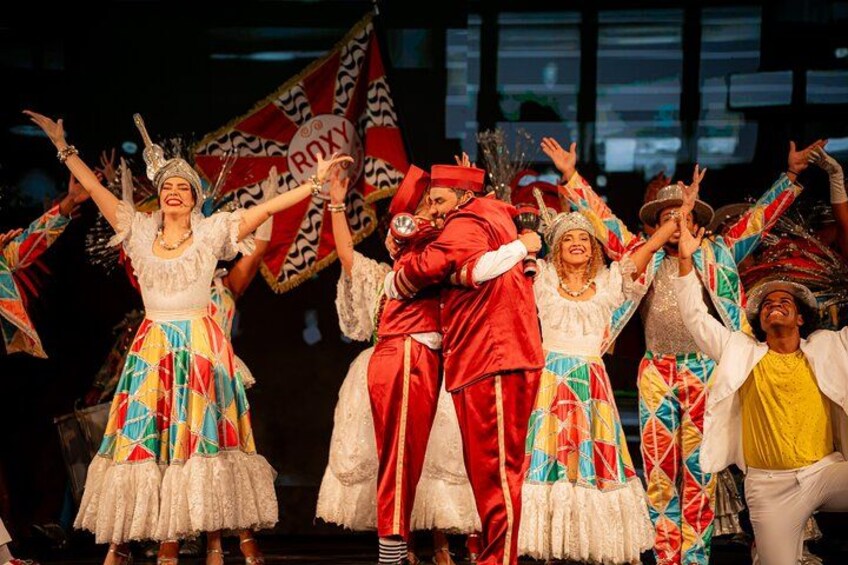 A group of people in colorful traditional costumes performing on stage. 4