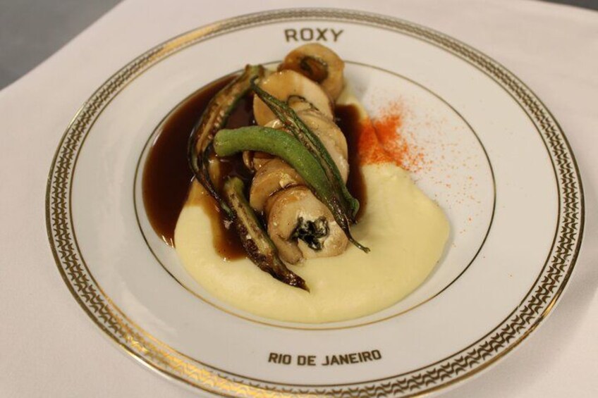 Een bord eten met een romige saus, groene groenten en een bruine saus, met de tekst 'RIO DE JANEIRO'. 2