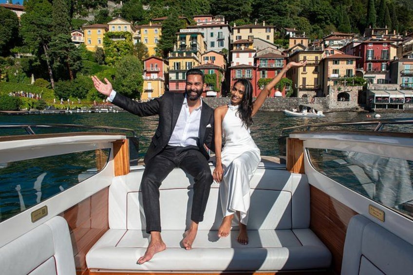 A couple on a boat with a scenic waterfront and colorful buildings in the background. 3