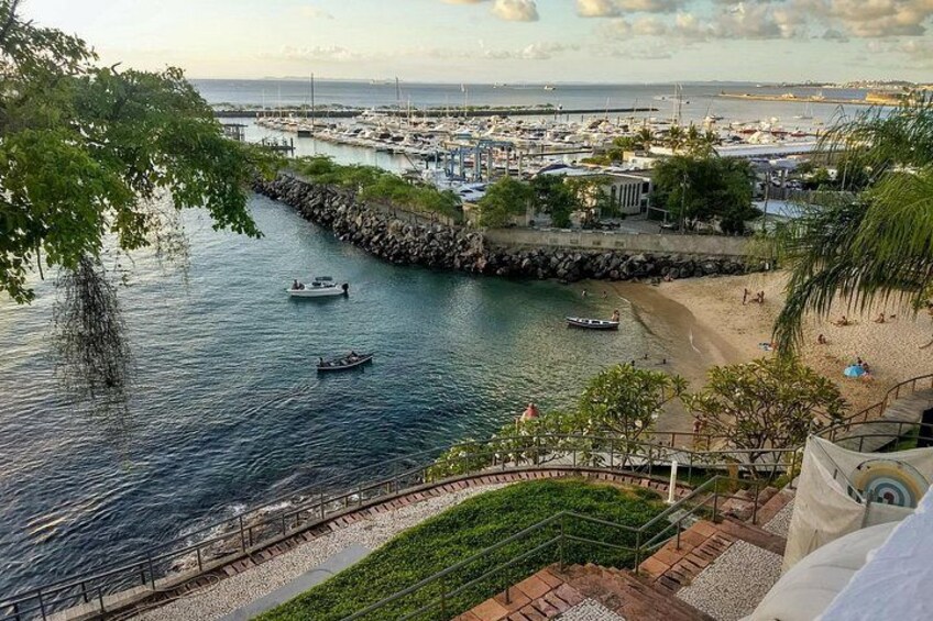 A coastal marina with boats, a sandy beach, and a stone wall. 3