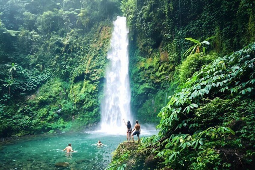 Ein Wasserfall, üppiges Grün und Menschen in einer natürlichen Umgebung. 1
