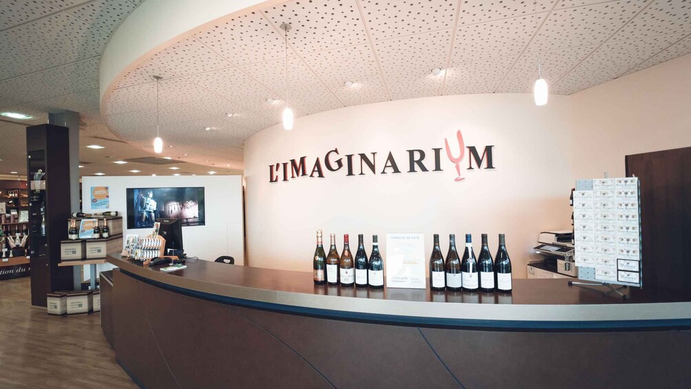 A wine tasting room with a counter displaying wine bottles and a sign reading 'L'Imaginary'. 5