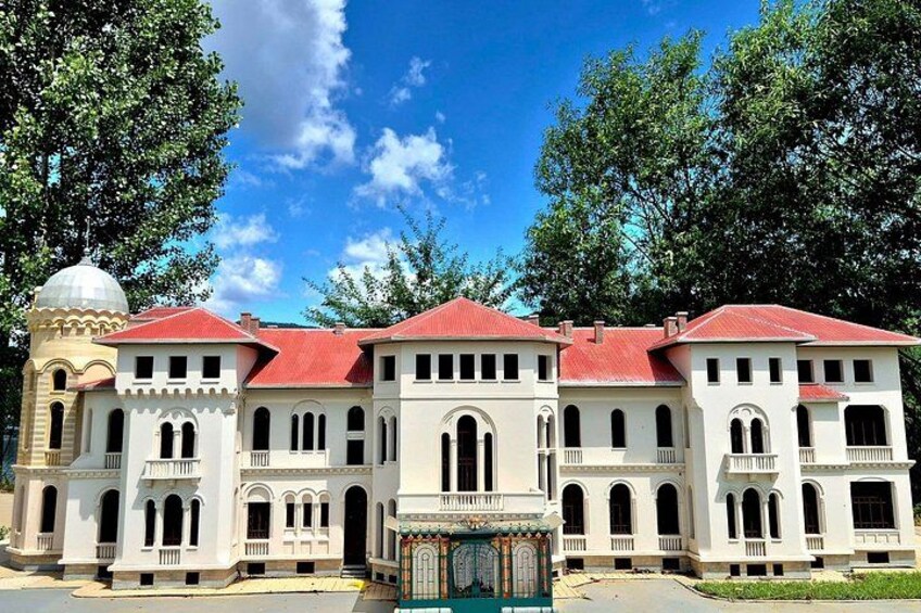 A large, white building with red roofs and arched windows, surrounded by trees. 5