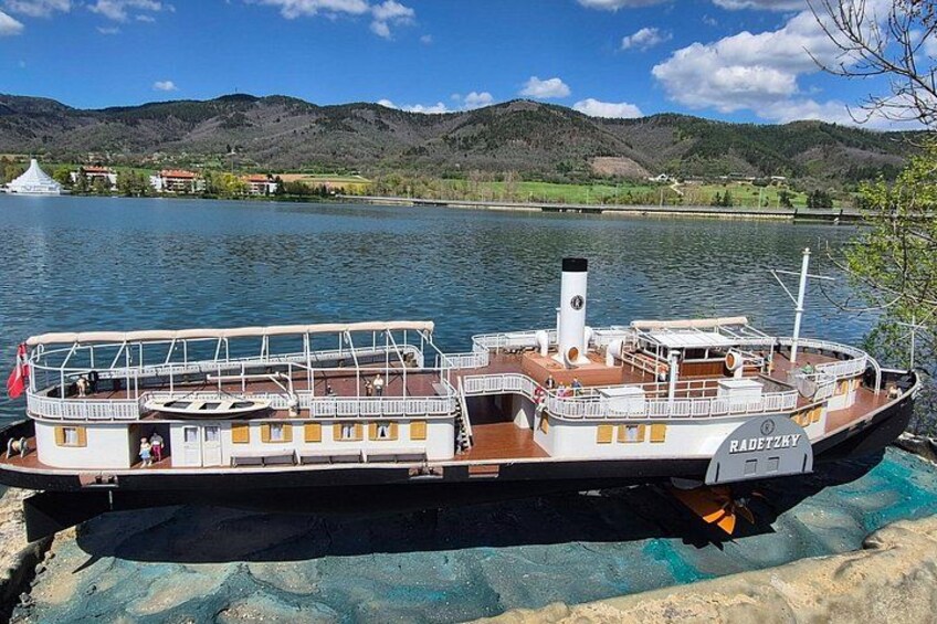 A riverboat docked at a pier with a mountainous landscape in the background. 3