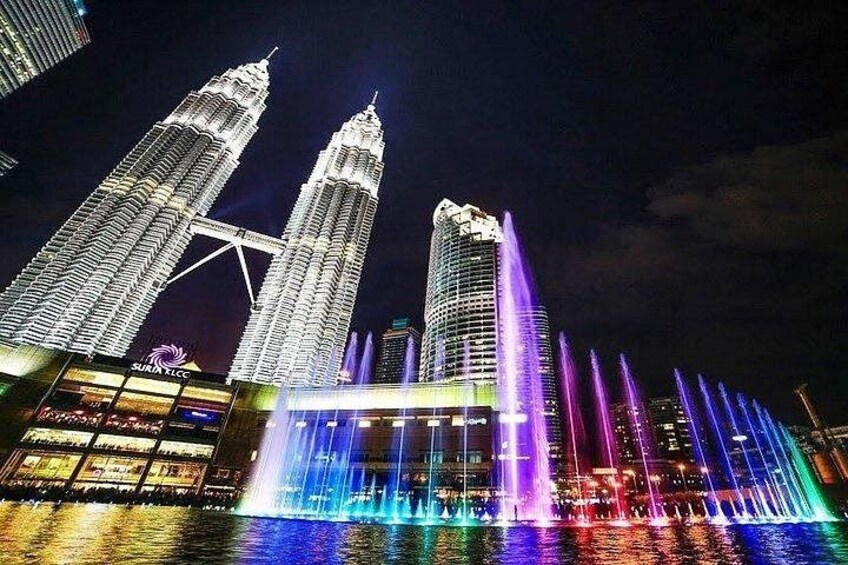 The Petronas Twin Towers illuminated at night with colorful water fountains. 1