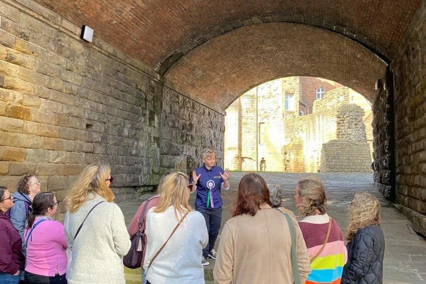 A group of people listening to a guide in a stone archway. 5