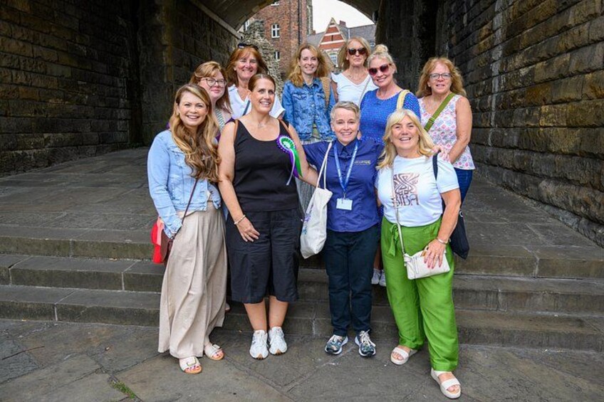 A group of people standing on stone steps in a stone-walled alleyway. 1