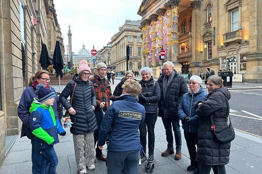 A group of people standing on a city street with buildings and a dome in the background. 2