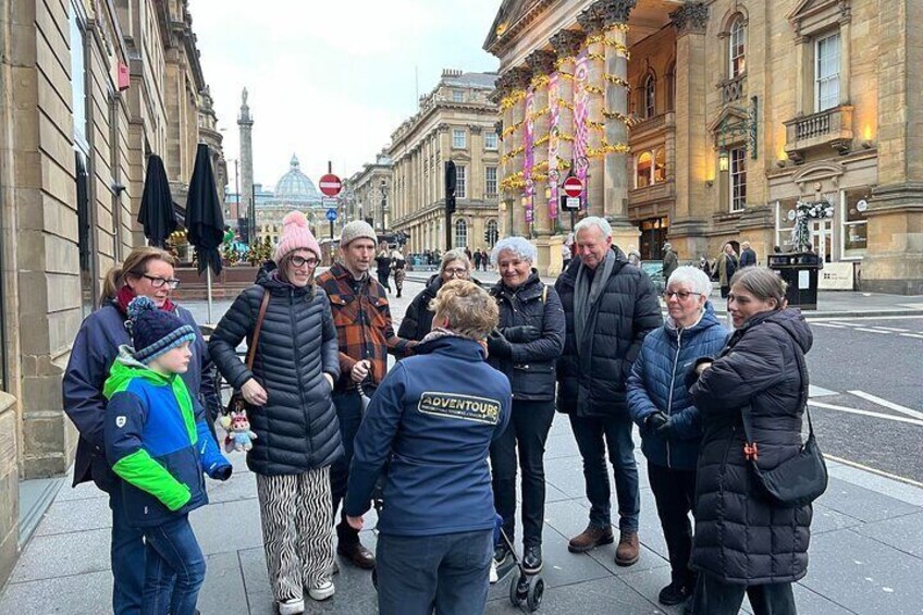 Un gruppo di persone in piedi su una strada cittadina, con edifici storici sullo sfondo. 2