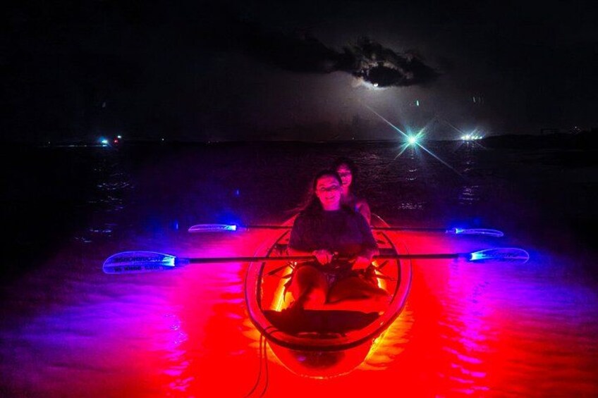 Imbarcazione con due persone su un corso d'acqua illuminato da luci rosse e blu di notte. 4
