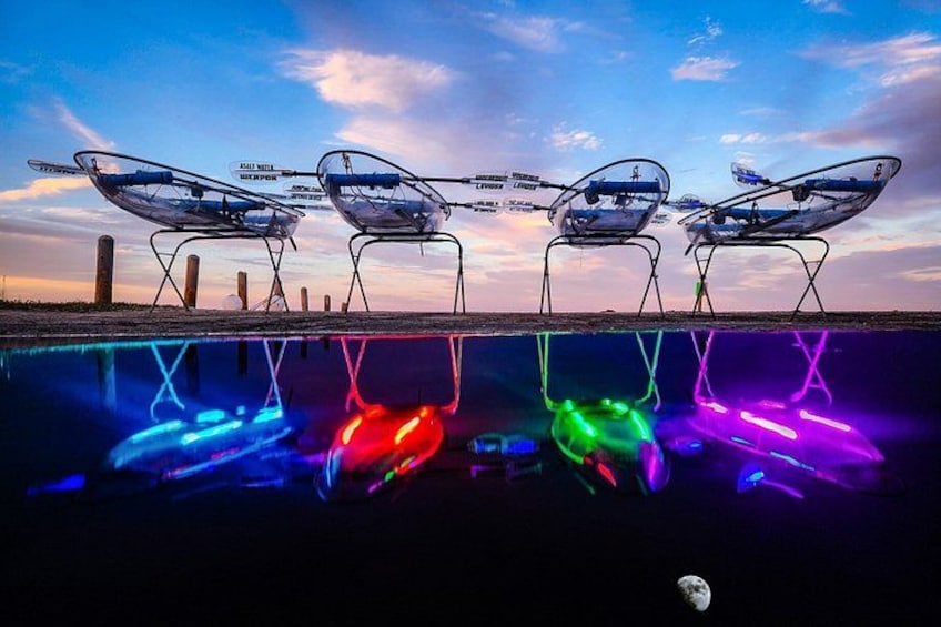 Four chairs with solar panels, a sunset sky, and colorful light reflections on water. 2