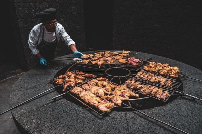 A person grilling various meats on a large outdoor grill. 2