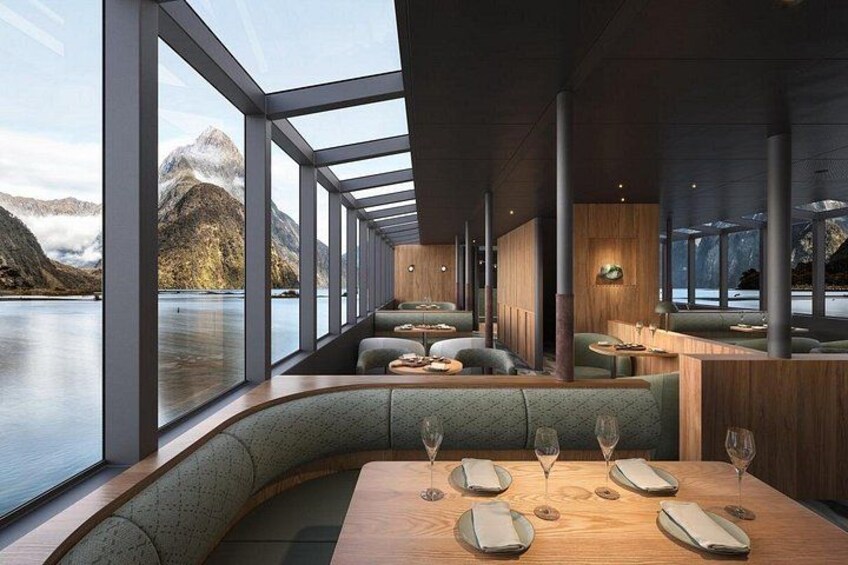 A modern restaurant with large windows overlooking a lake and mountains. 2