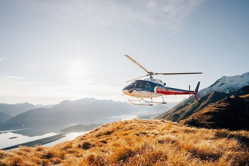 A helicopter flying over a mountainous landscape with a lake below. 2